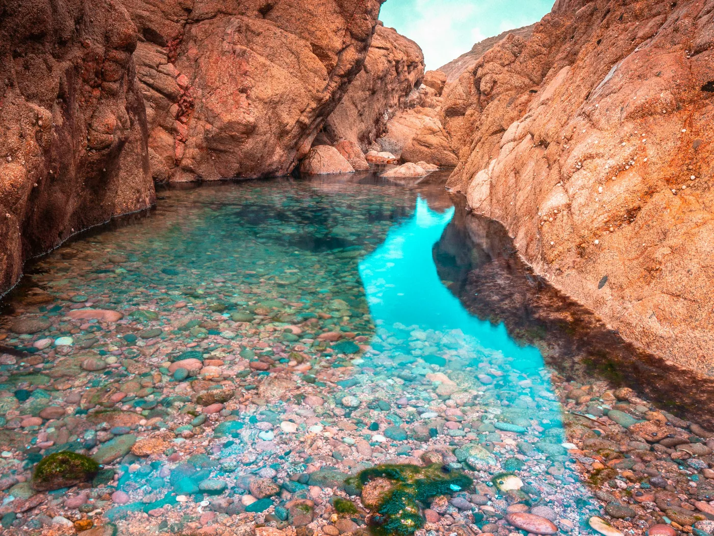 Clear turquoise plunge pool below rock cliffs